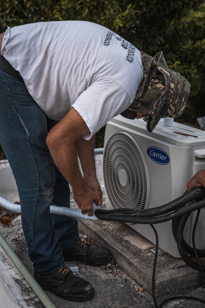 services-01 A technician performs maintenance on an outdoor air conditioning unit, focusing on hose connections.