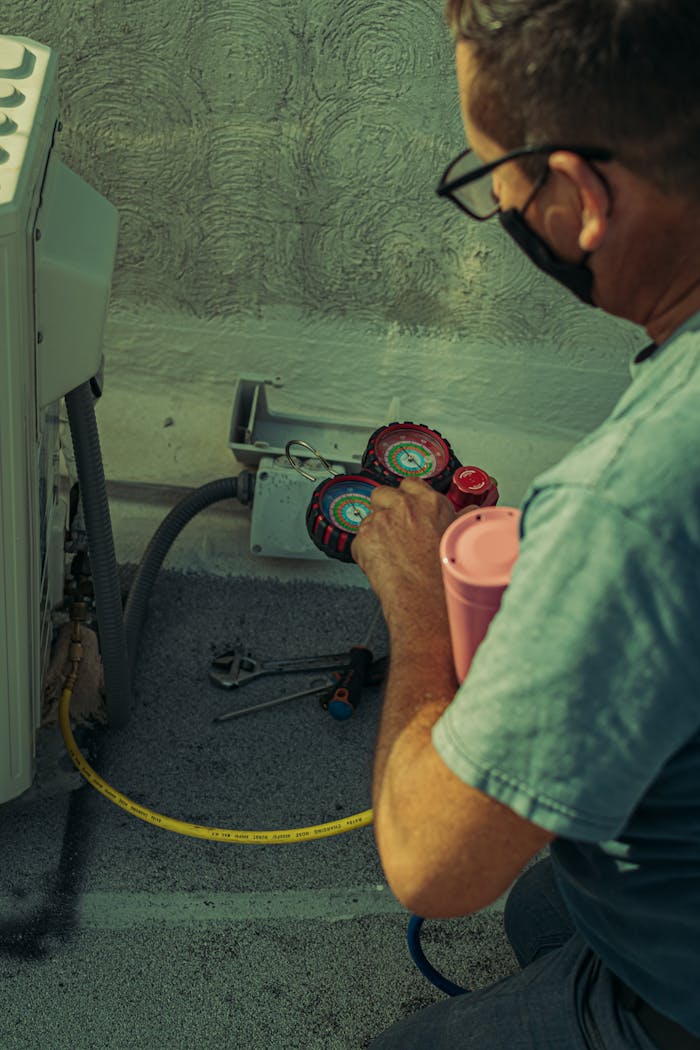 services-02 A technician checks and repairs an HVAC system outdoors using tools and gauges.